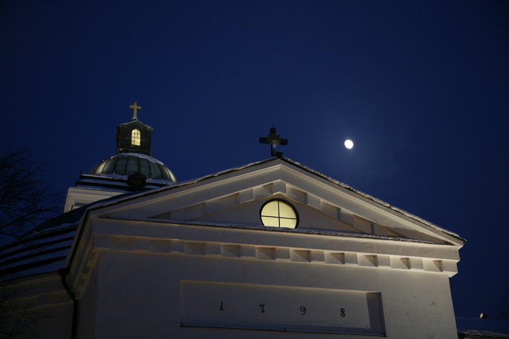 Hämenlinnan kirkon kattosiluetti tummaa talvitaivasta vasten.