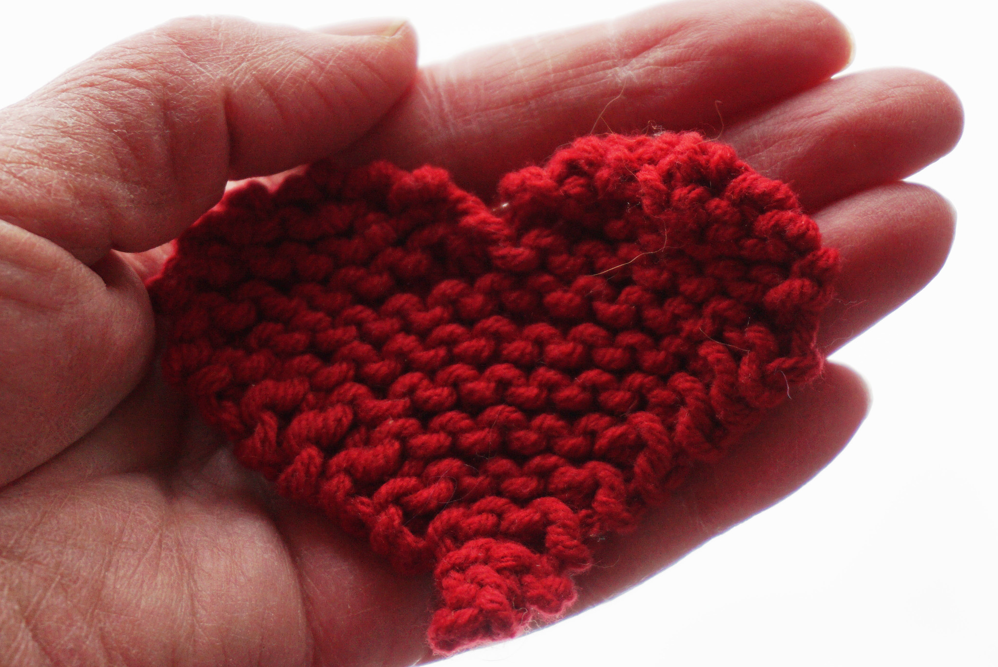 Kädessä neulottu punainen sydän.