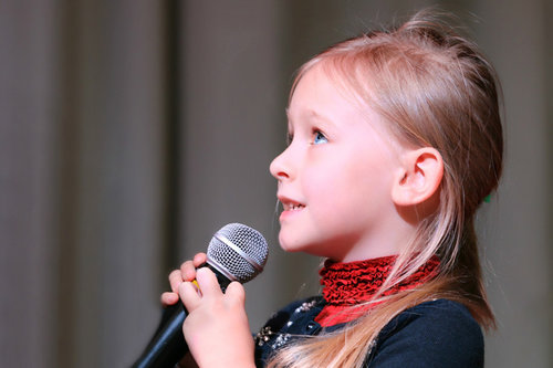 Nuori tyttö laulaa mikrofoniin. Hämeenlinna-Vanajan seurakunta.